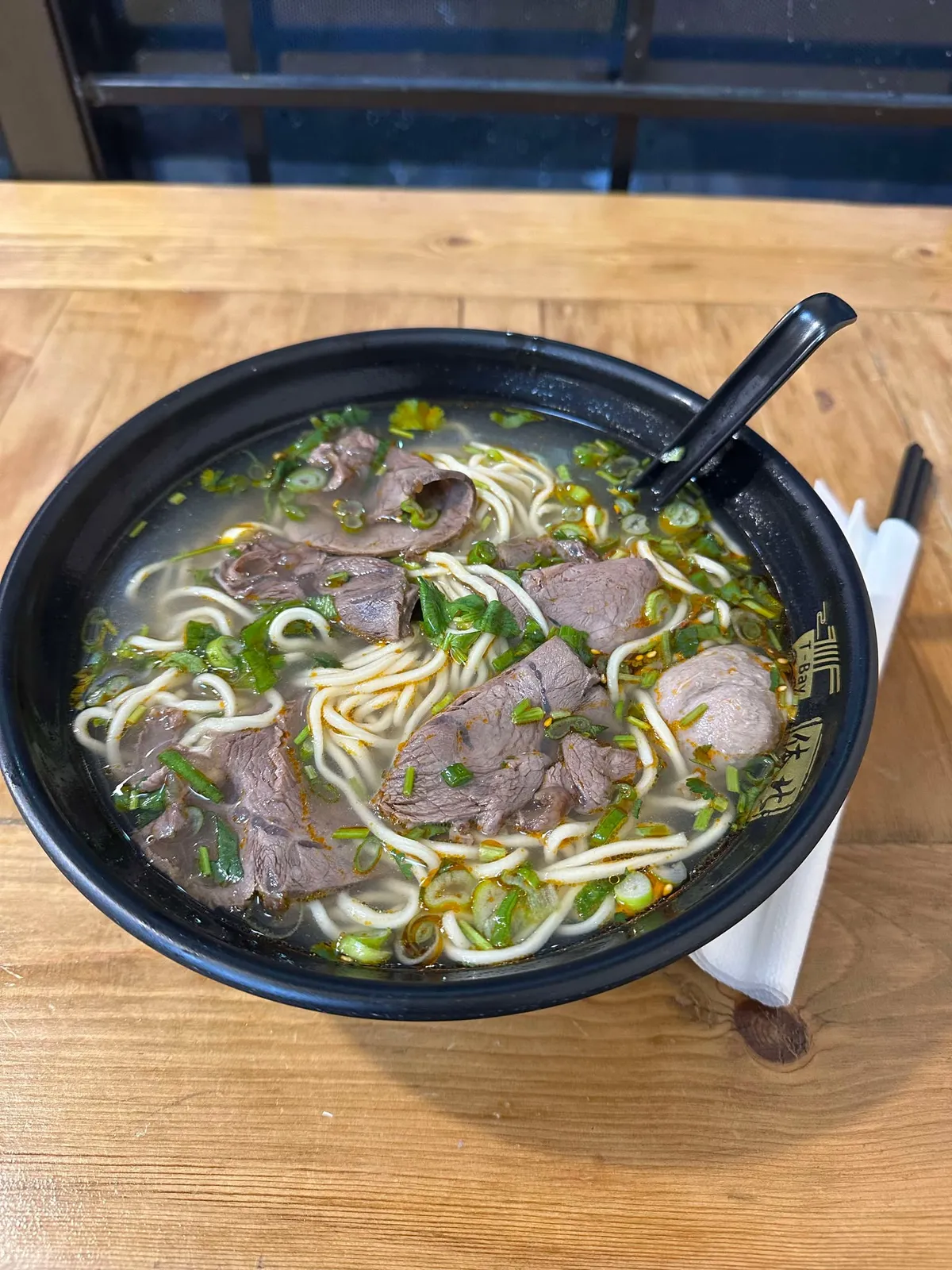 Bowl of beef noodle soup on a wooden table
